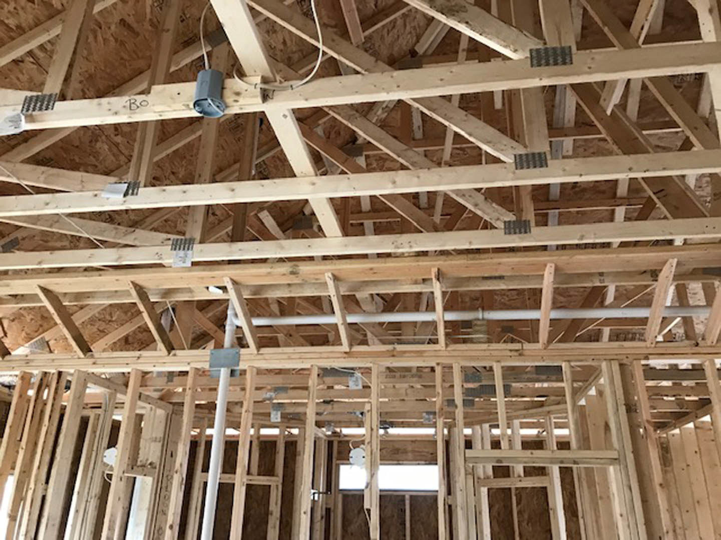Exposed wood framing and beams with building insulation in a partially constructed residential interior