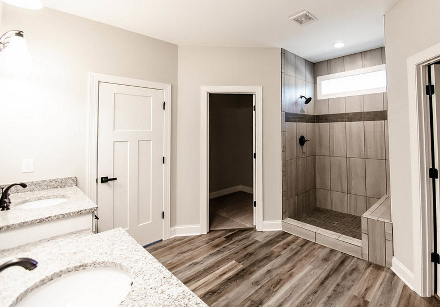 Modern bathroom featuring a glass-enclosed shower, white ceramic sink with chrome faucet, light tile flooring, white painted walls, and a square white wall outlet near a paneled