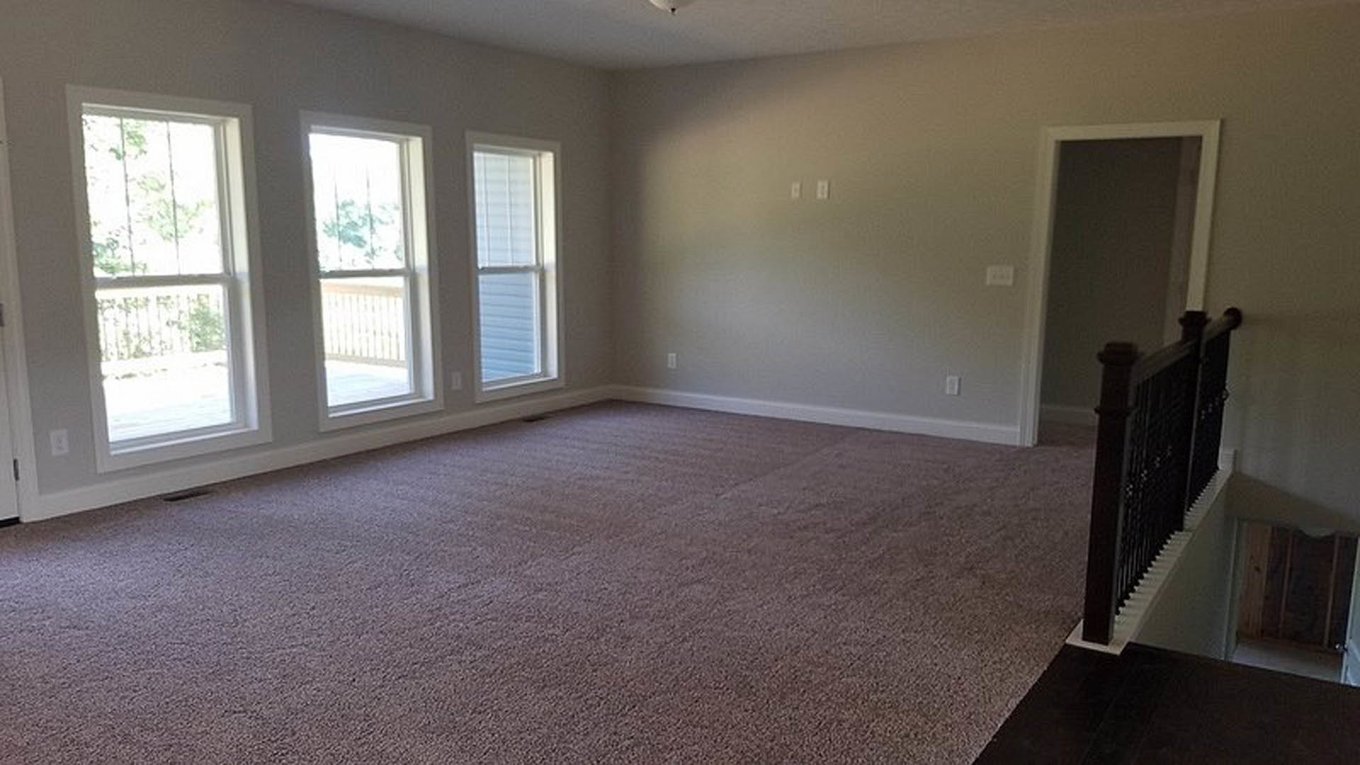 Carpeted room with multiple windows, white walls, and wood trim
