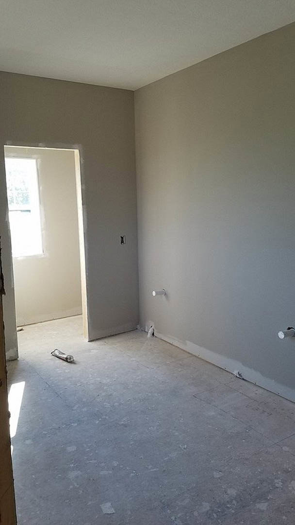 White plaster walls, wood flooring, hinged door on the left, open doorway on the right, flat ceiling, minimal trim
