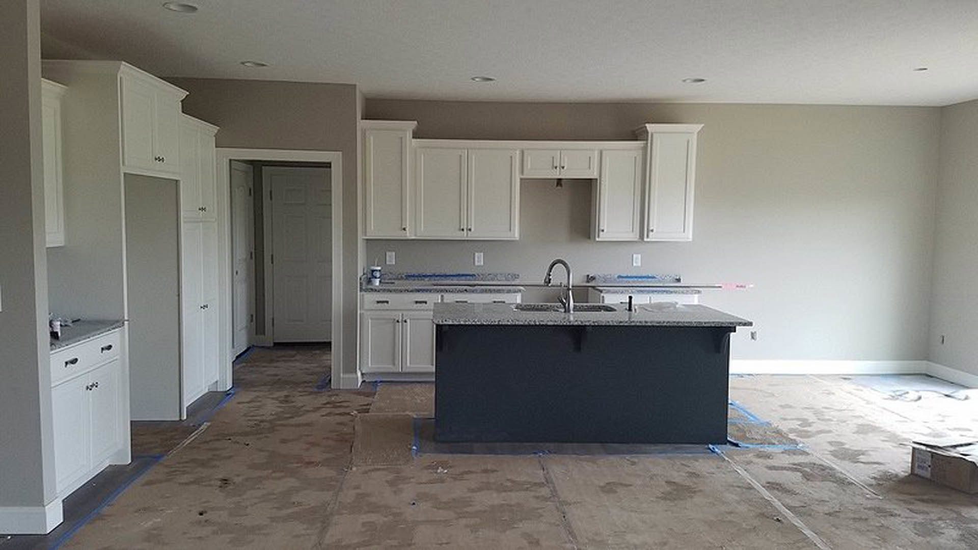 Bright kitchen featuring white tile backsplash, stainless steel sink set in quartz countertop, light wood cabinetry, and neutral tile flooring
