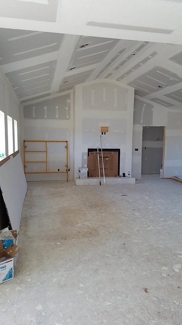 Living room with white plaster walls, wood beam ceiling, fireplace, and white door framed in wood