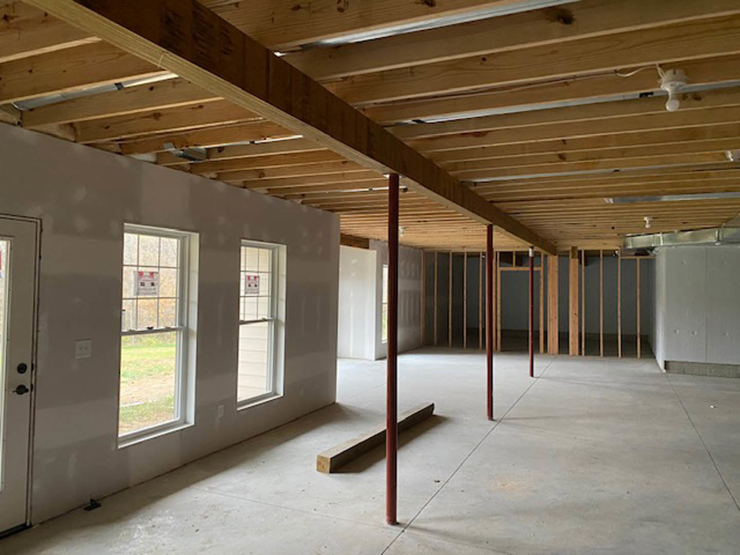 Living room with exposed wooden ceiling beams, large windows, neutral walls, and hardwood flooring