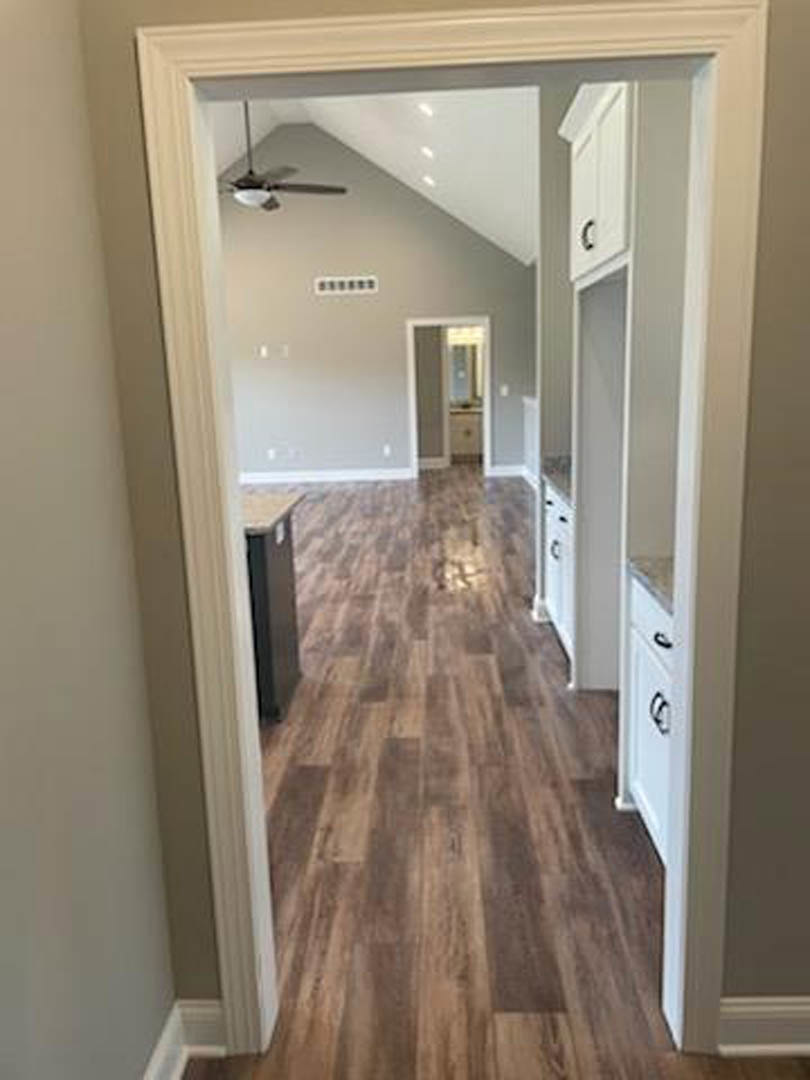 Kitchen and dining room with wood laminate flooring, white walls, ceiling fan with light, visible doorway frame