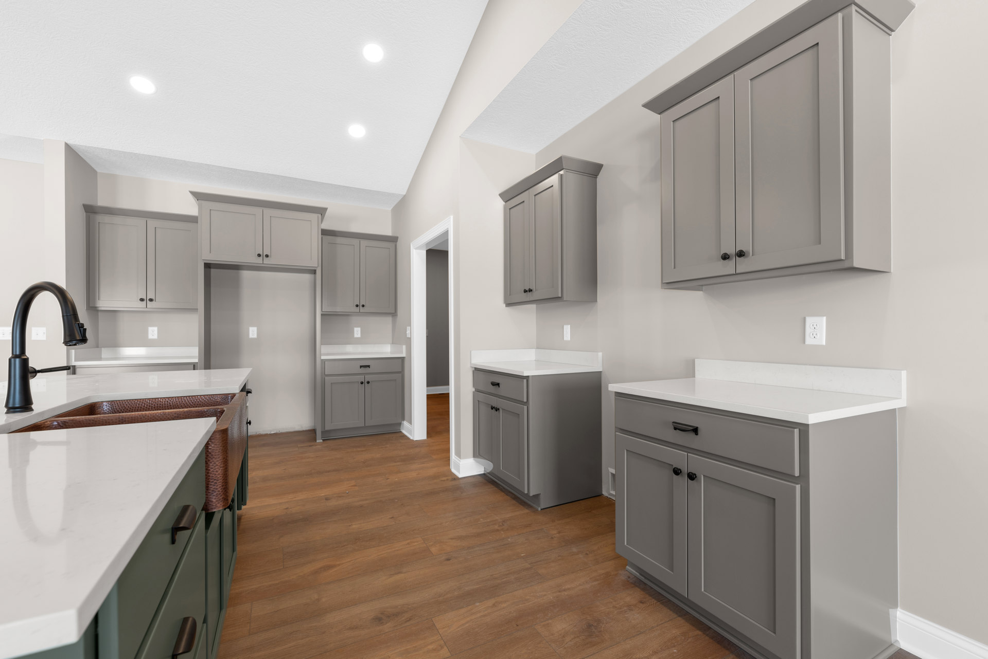 Gray shaker cabinets with matte black handles, white quartz countertops, copper undermount sink, black gooseneck faucet, white tile backsplash, light wood flooring