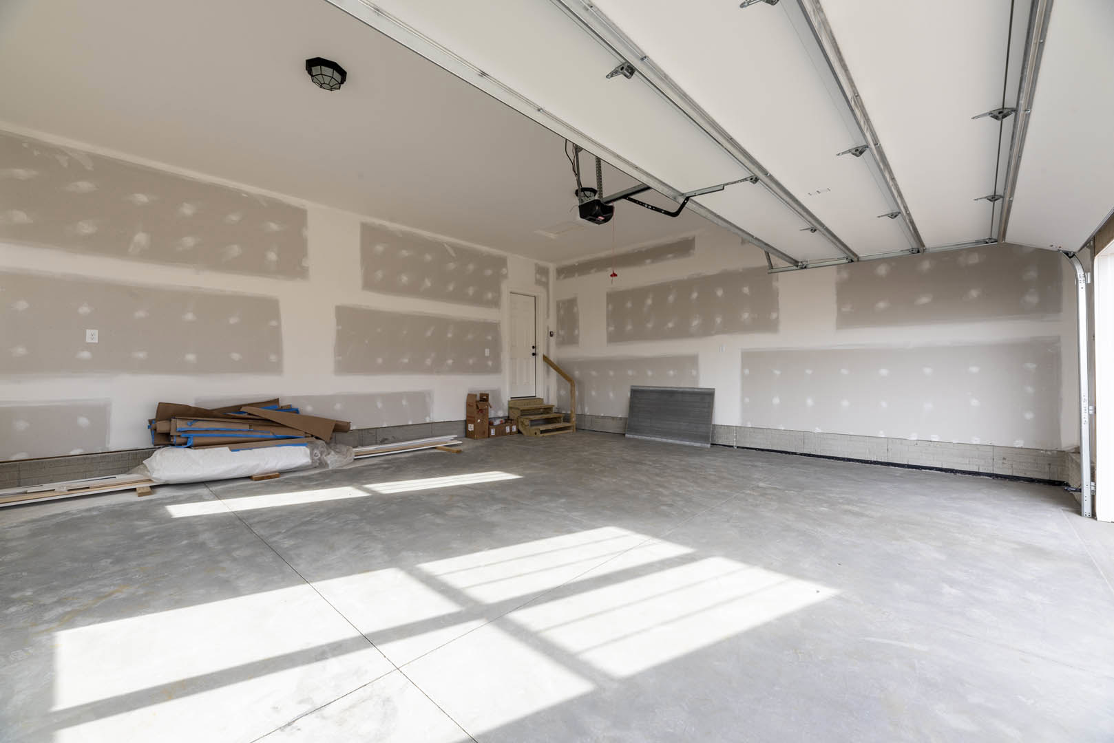 White plaster wall and ceiling in a modern room, black and white light fixture overhead, light reflecting on smooth flooring, metal surface detail, brown surface with rolled paper