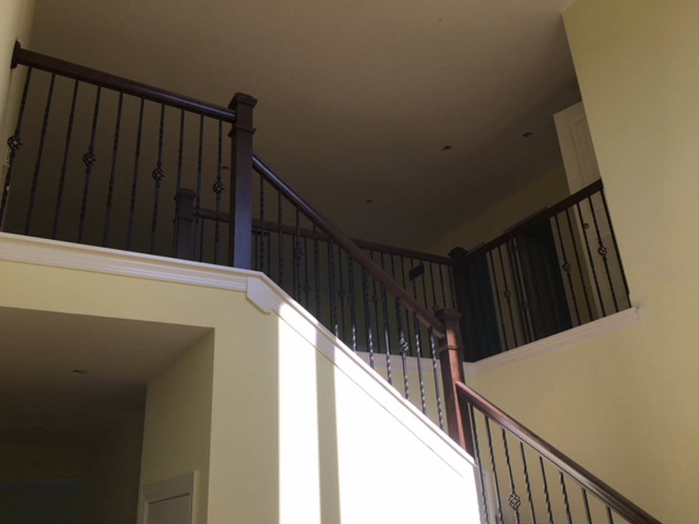 Black metal railings on a modern staircase with white walls and a white door in the background