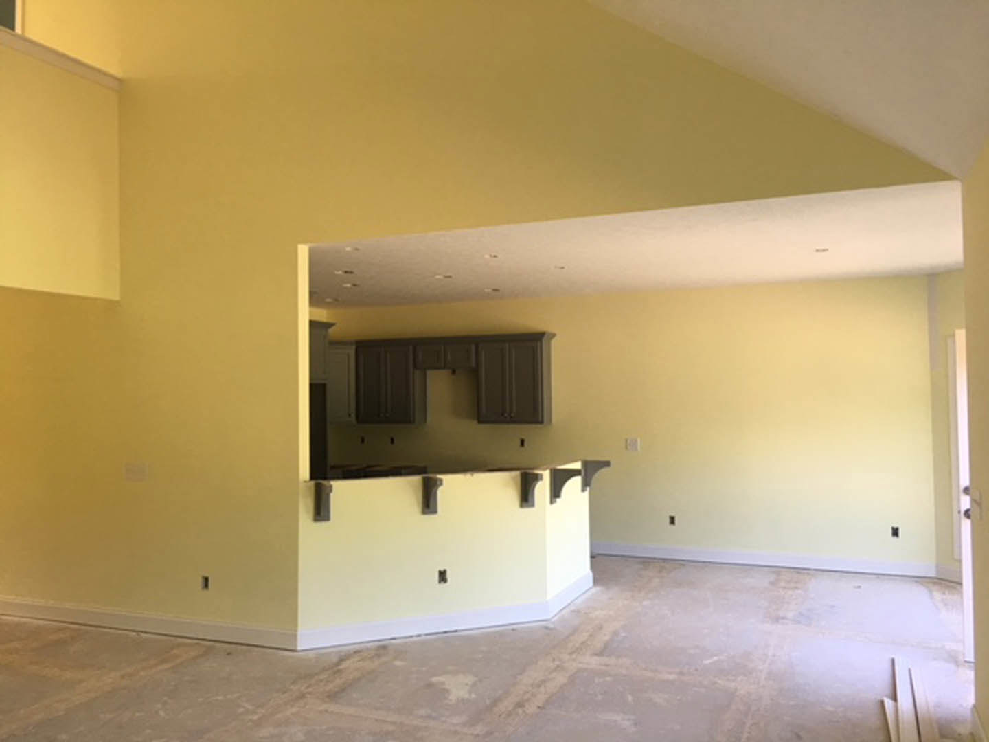 Modern kitchen with light tile flooring, white plaster walls, sleek cabinetry, concrete countertops, ceiling fan, and wall-mounted light fixture