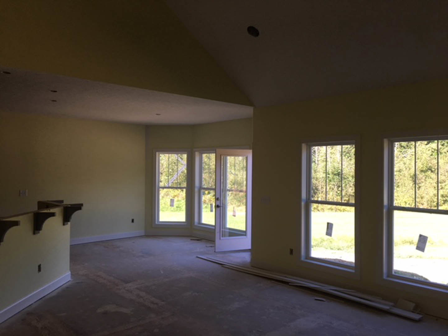 Bright room featuring large windows, white walls, built-in sink with chrome faucet, light wood flooring, and electrical outlet on the wall.