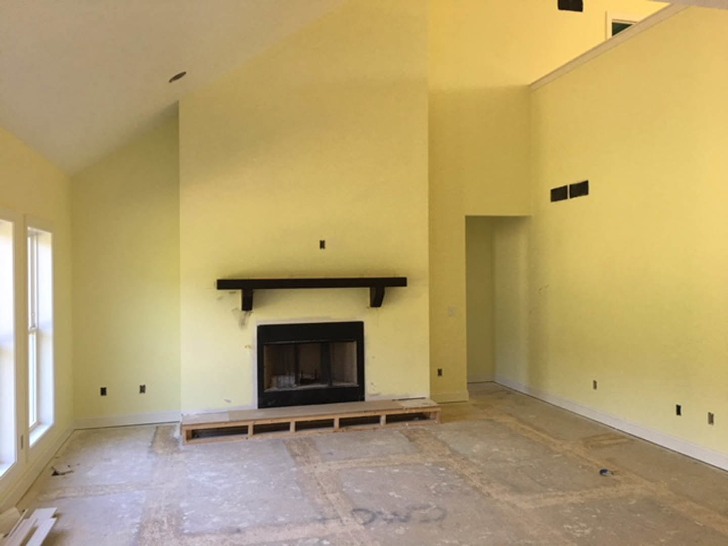 Modern living room featuring a sleek black fireplace set into a white plaster wall, concrete flooring, and minimalist interior design elements.