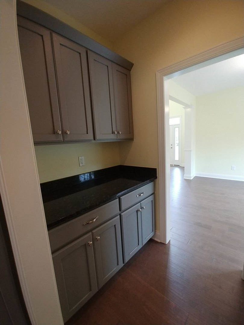 Kitchen with grey cabinets, black countertops, dark wood flooring, and white walls