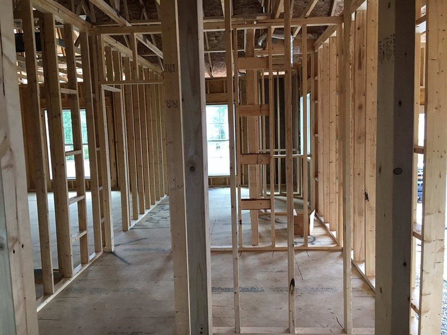 Wood-framed room with exposed beams, unfinished concrete floor, and large window letting in natural light