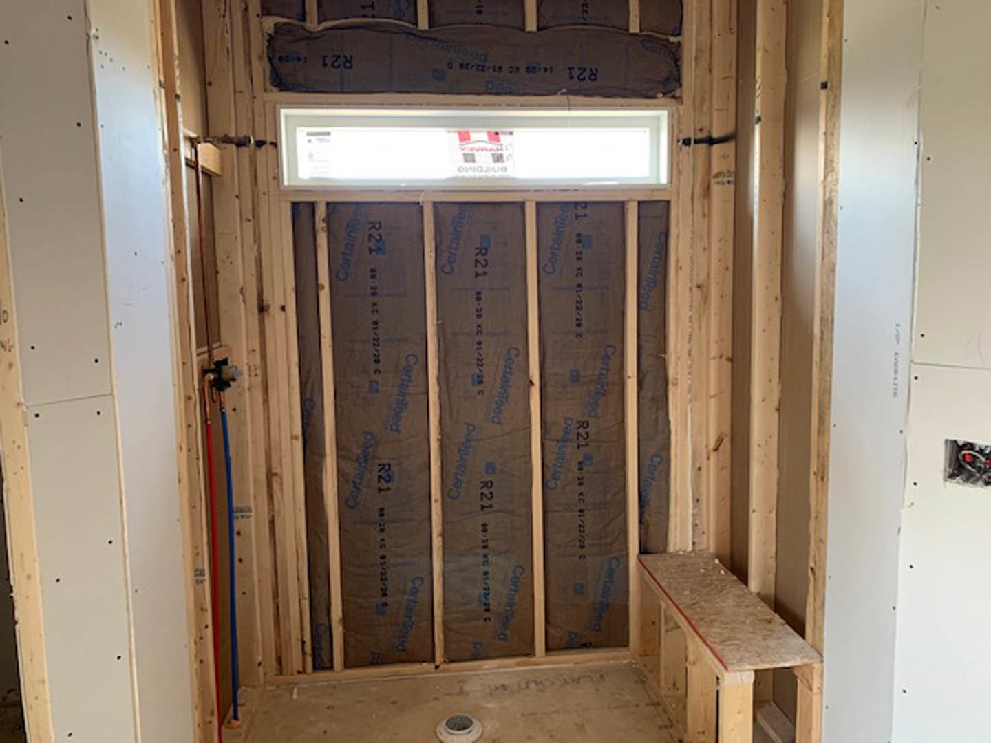 Modern room with light wood flooring, plaster walls, large window, and a wooden table; black and blue materials accent the wall.