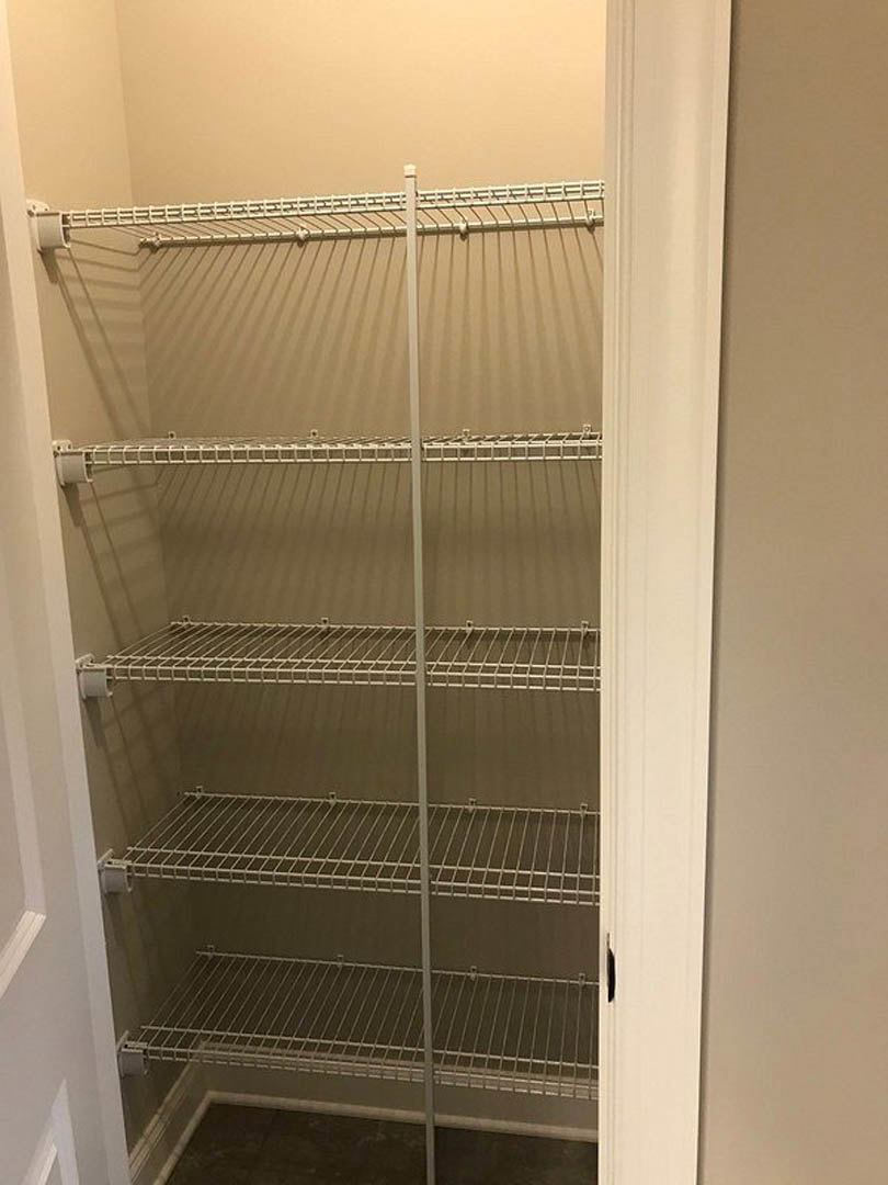 White closet interior with perforated metal shelving and smooth painted walls