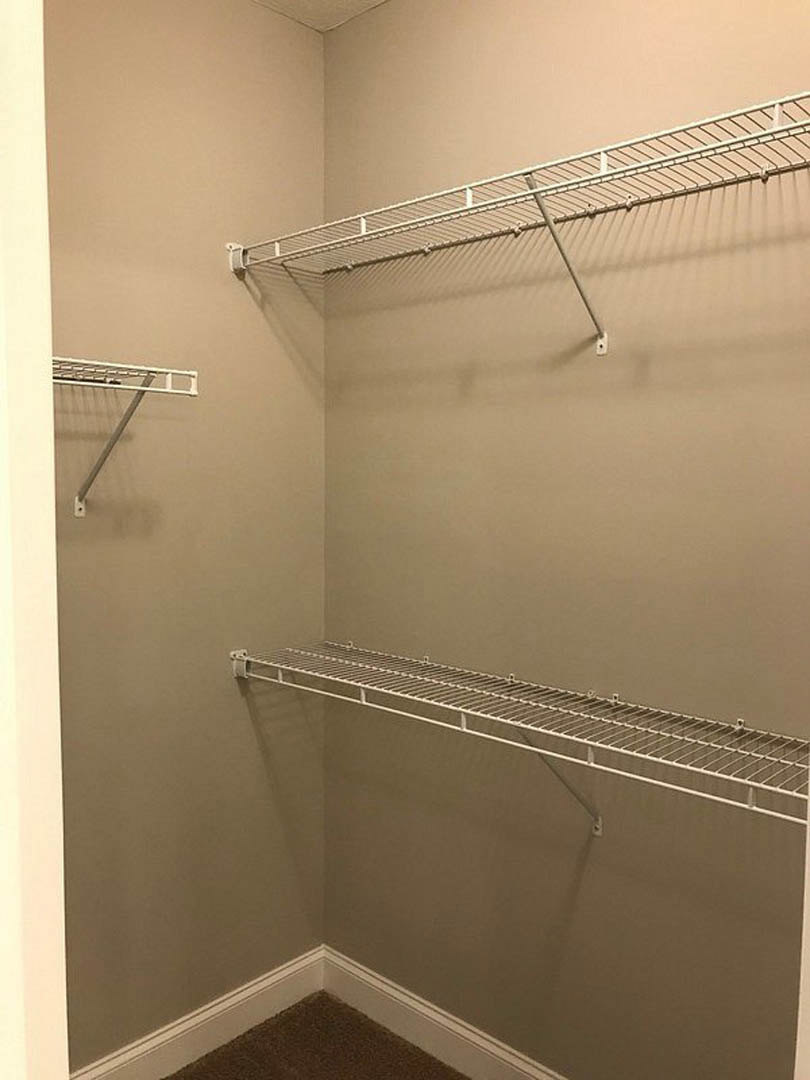 Walk-in closet featuring white wire shelving with integrated hanging rod, light-colored walls, and tile flooring.
