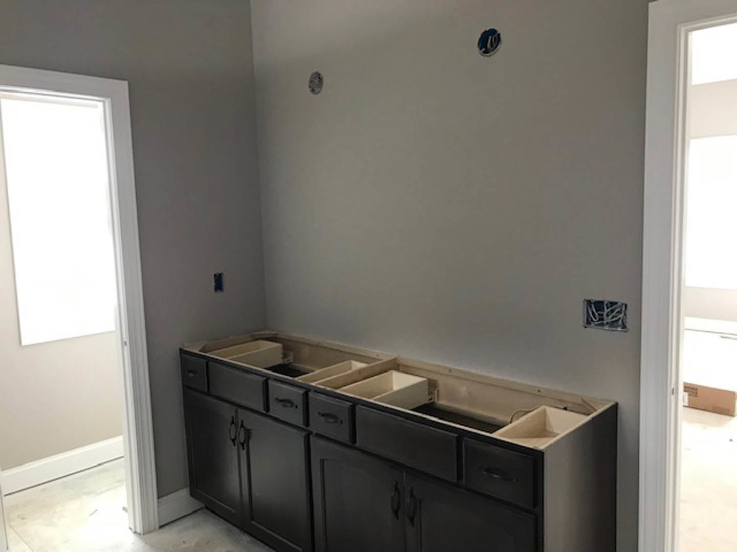 Modern kitchen featuring white cabinetry, black backsplash, stone countertop, stainless steel sink, and chrome faucet.