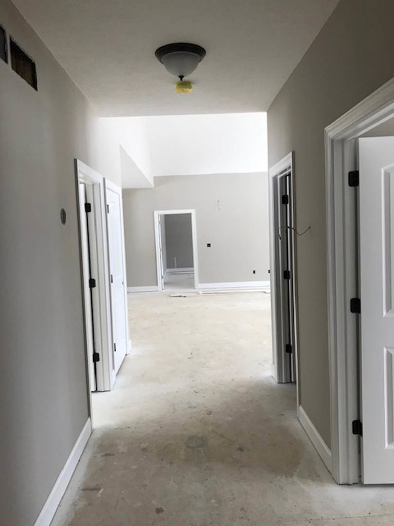 Hallway with smooth white walls, white paneled doors, white trim, and light-colored flooring