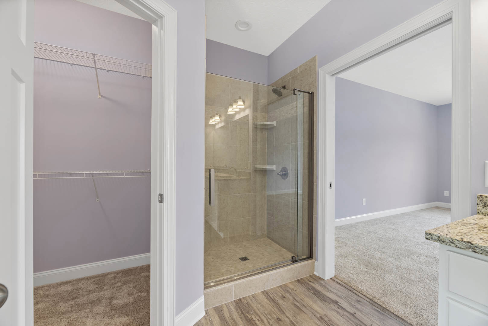 Bathroom featuring a glass shower enclosure, tiled walls, white shelving, wood and carpet flooring, and a modern countertop.