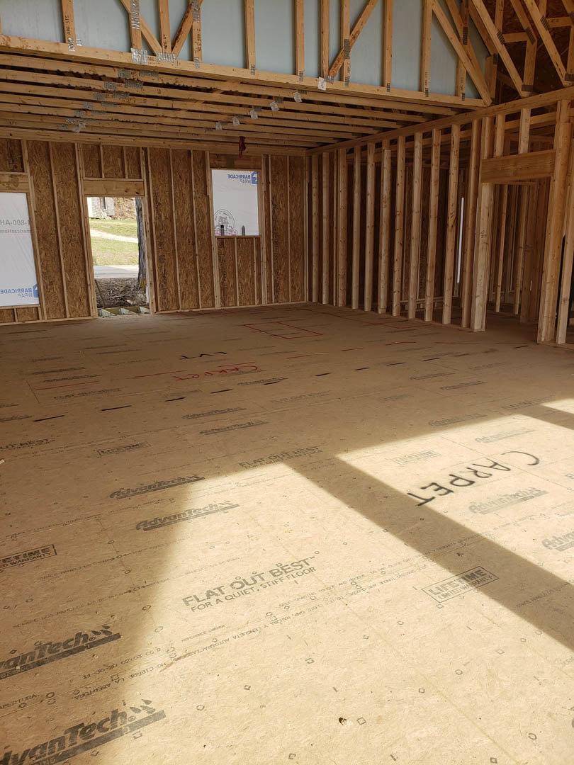 Spacious room featuring exposed wood ceiling beams, large windows, and hardwood flooring