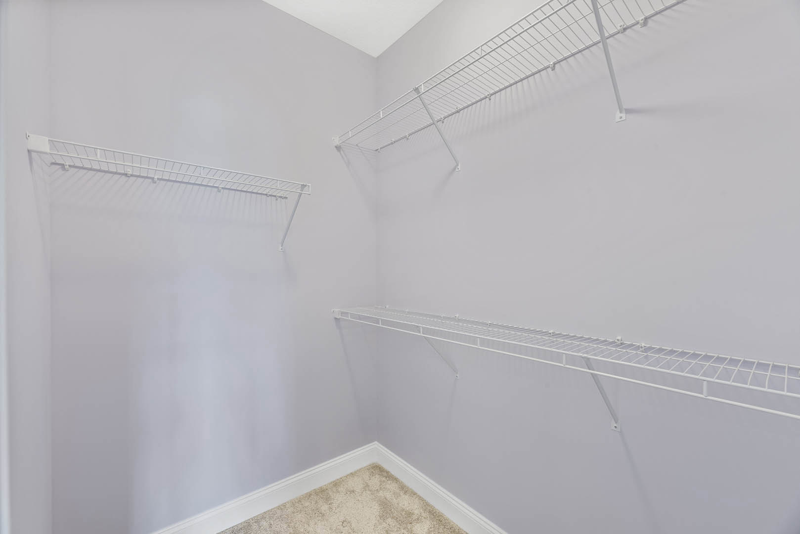 White built-in shelves mounted on a white plaster wall beneath a white ceiling, with light carpet flooring visible.