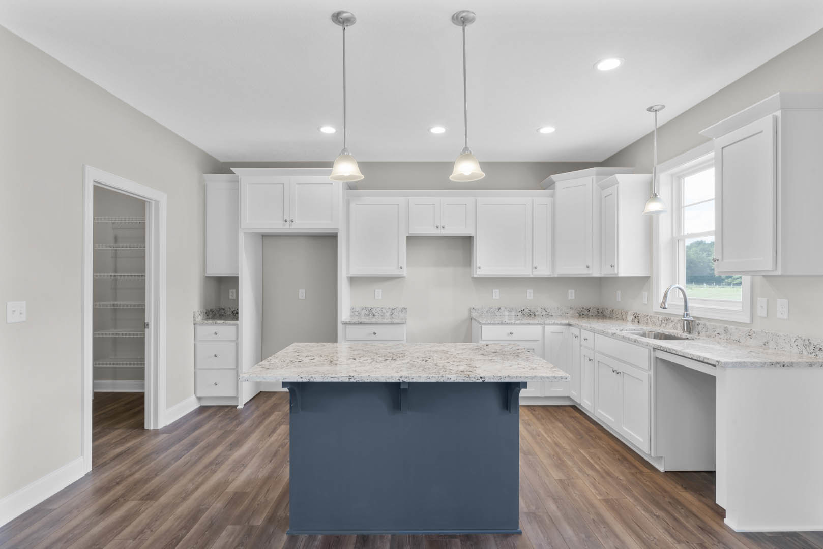Spacious kitchen featuring a large white island with quartz countertop, pendant lights hanging from a white ceiling, tile flooring, white cabinetry, stainless steel sink, and