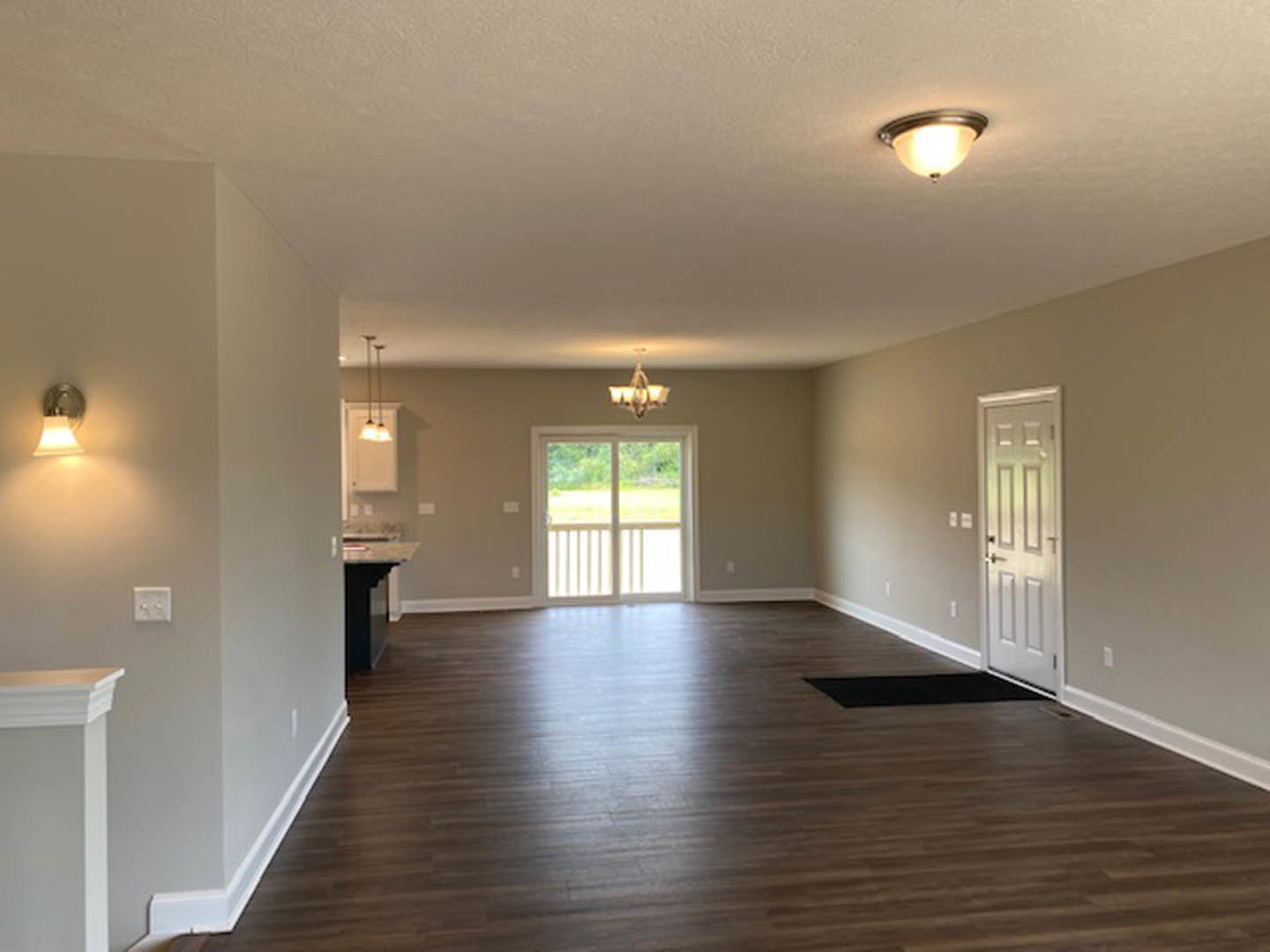 White paneled doors with brushed metal handles, wood laminate flooring, white plaster walls, dual wall switches, and a ceiling chandelier partially visible in the background