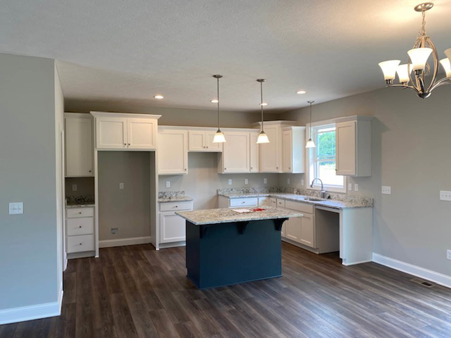 Kitchen featuring marble countertops, wood flooring, white cabinetry, stainless steel appliances, and a central island with a marble top.