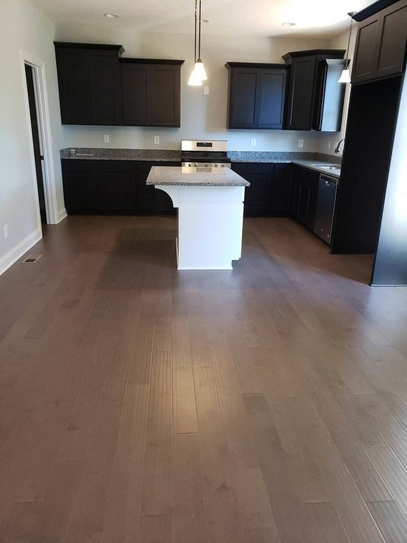 White kitchen island with granite countertop, dark wood cabinets, tile flooring, stainless steel sink, and bell-shaped pendant light fixtures