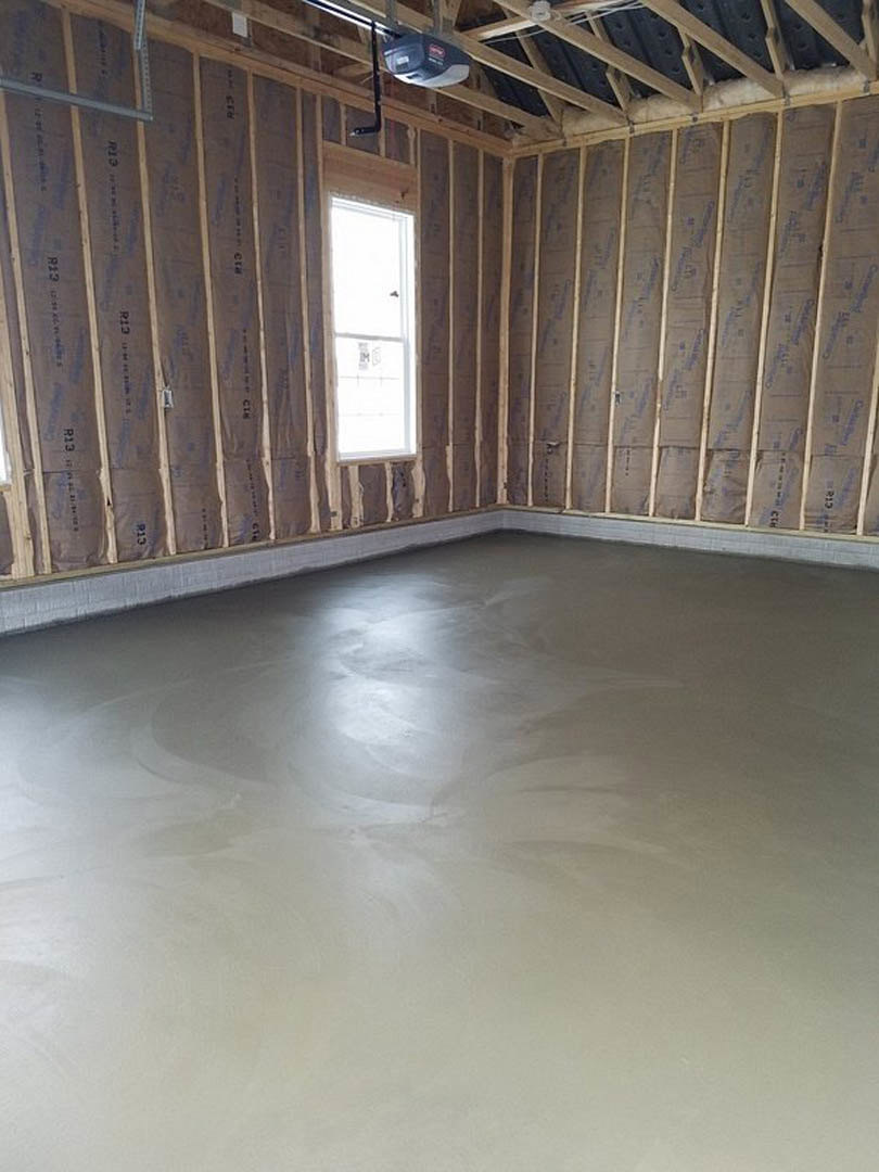 Concrete floor with sunlight, white door featuring glass window, exposed wooden ceiling beams, black roof panels, and neutral walls in a modern interior room.