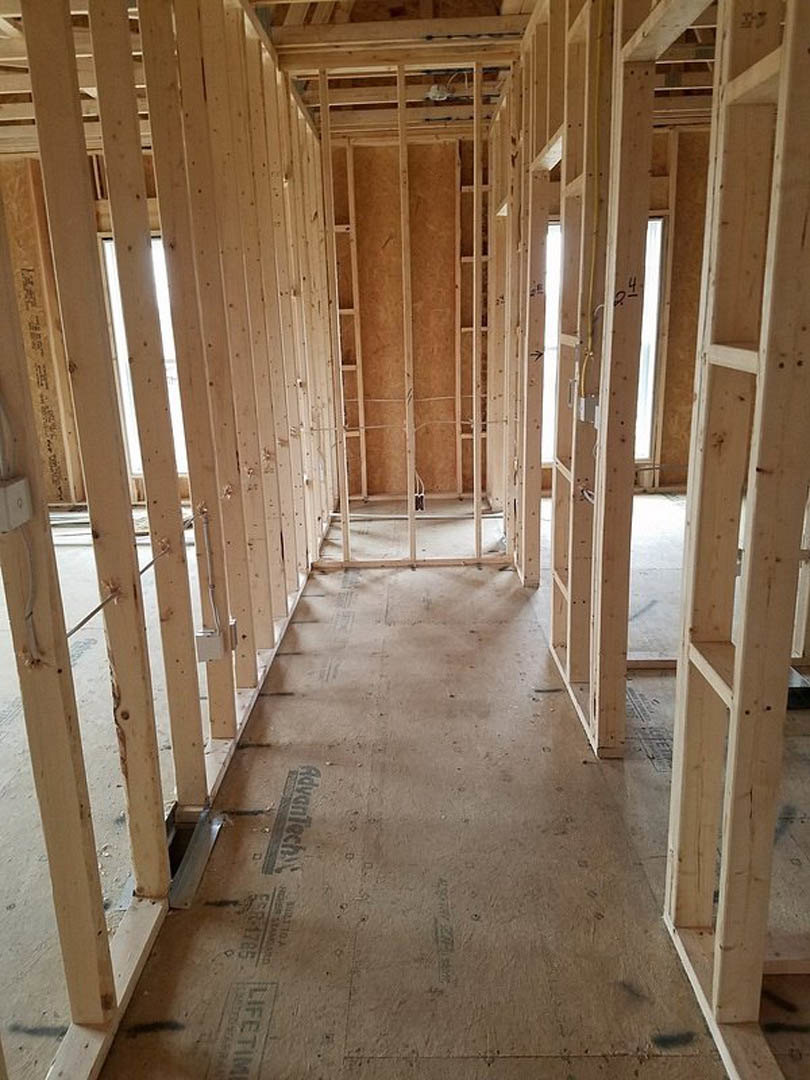 Exposed wood framing and beams with unfinished walls and ceiling, construction materials visible throughout interior room