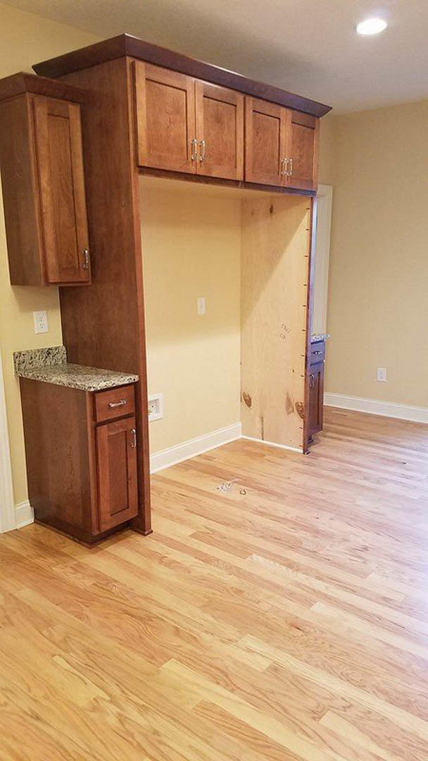 Modern kitchen with wooden cabinets, marble countertops, hardwood flooring, and white walls