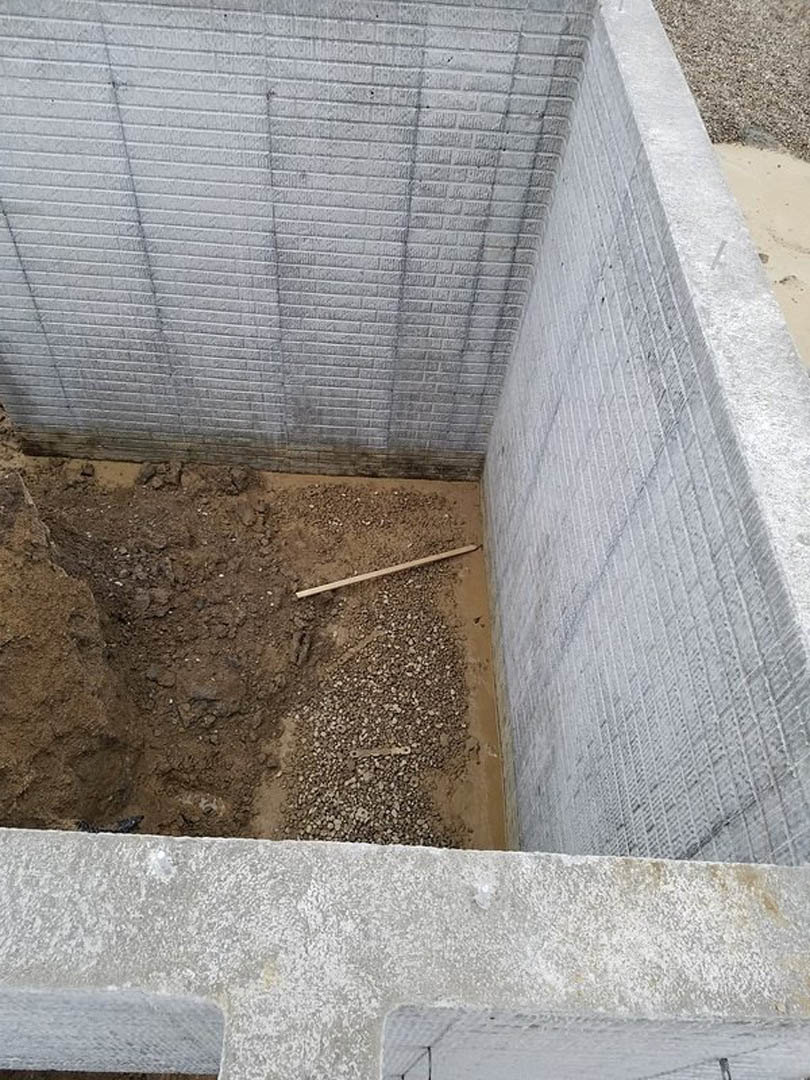 Concrete foundation surrounded by dirt and gravel, outdoor construction site with exposed cement and earth