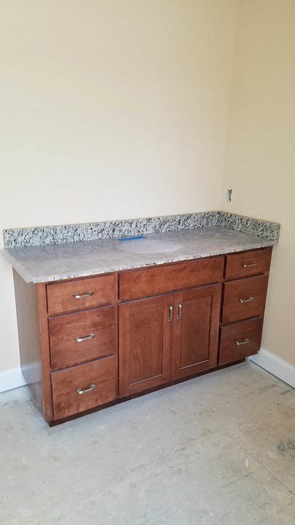 Marble countertop with wood drawers, chrome faucet, and tile floor in a modern kitchen
