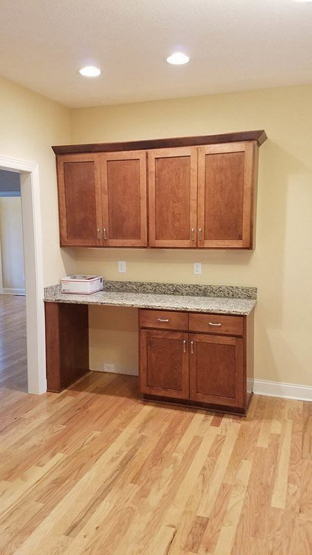 Kitchen featuring wooden cabinets, marble countertop, hardwood flooring, and tiled backsplash