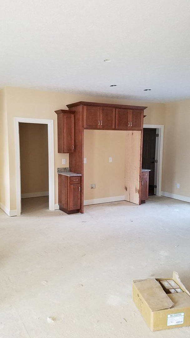 Open kitchen with light wood cabinets, stainless steel sink, white plaster walls, and hardwood flooring