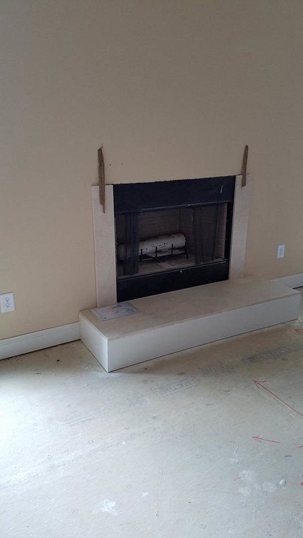 Modern living room with concrete floor, built-in fireplace featuring a roll of paper inside, white framed hearth, and white wall with black text.