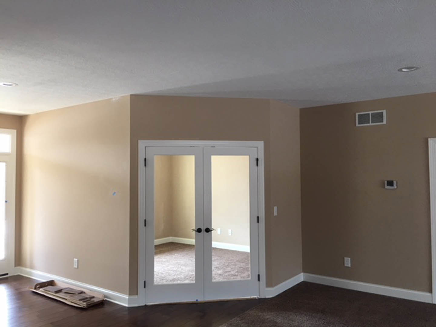 White-walled room with double doors featuring mirrored panels, large window, light wood flooring, and crown molding ceiling.