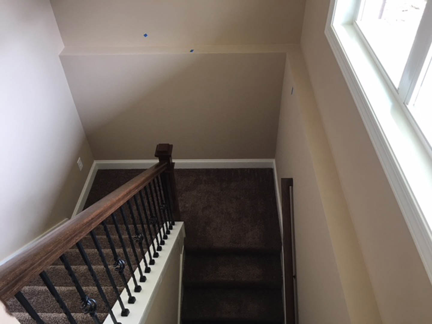 Carpeted staircase with wooden railing, white plaster walls, and decorative molding under natural daylight