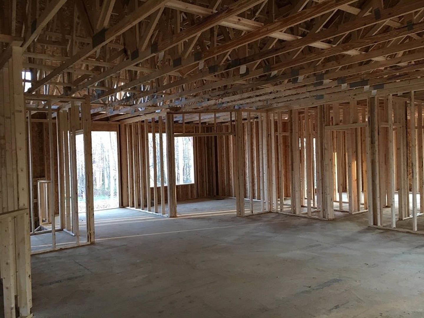 Exposed wood ceiling beams, concrete floor with white line, large window showing snow outside, metal pole with handle near wooden wall