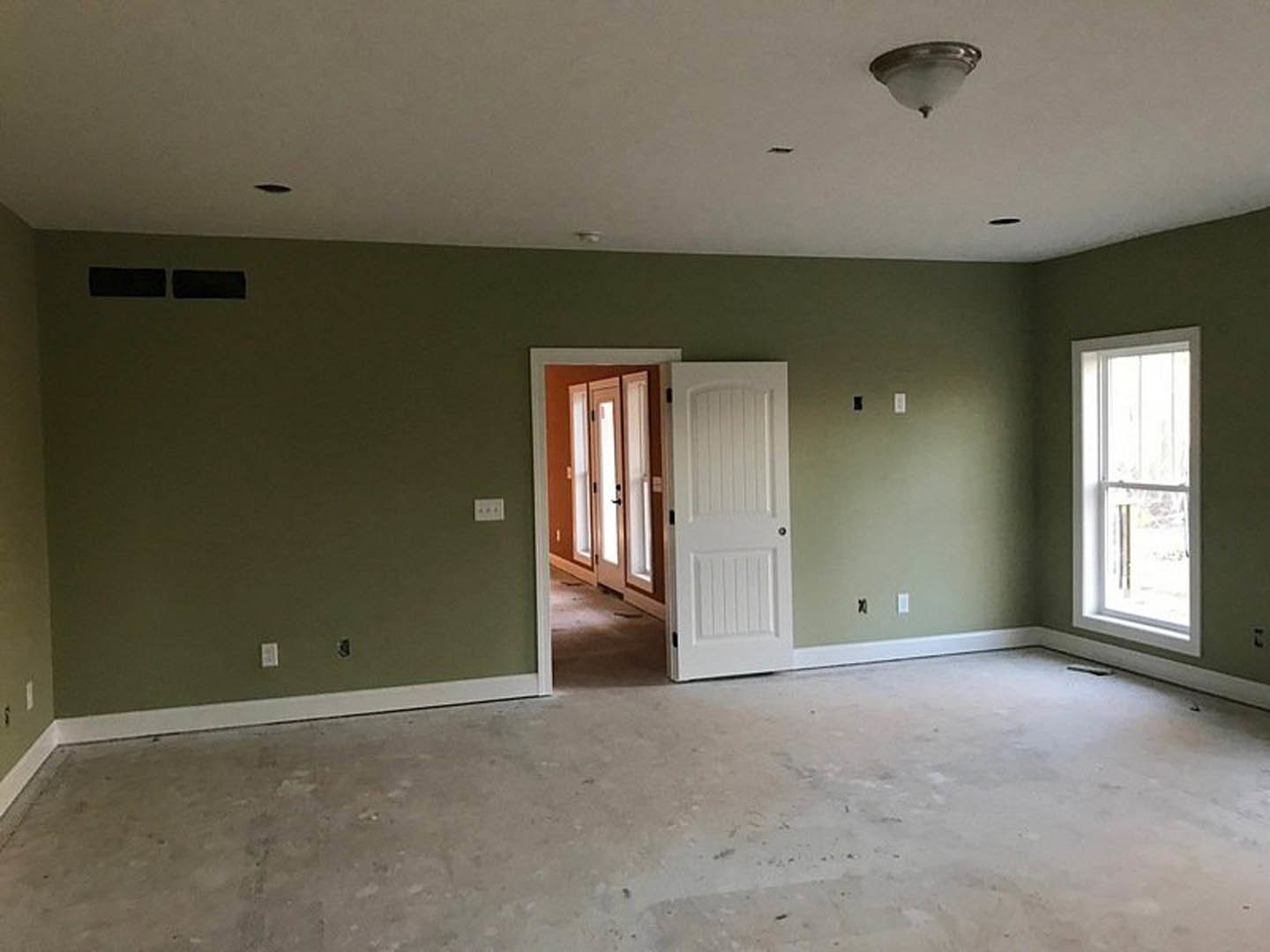 Green painted walls, white paneled door with silver doorknob, white-framed window, ceiling light fixture, light-colored flooring