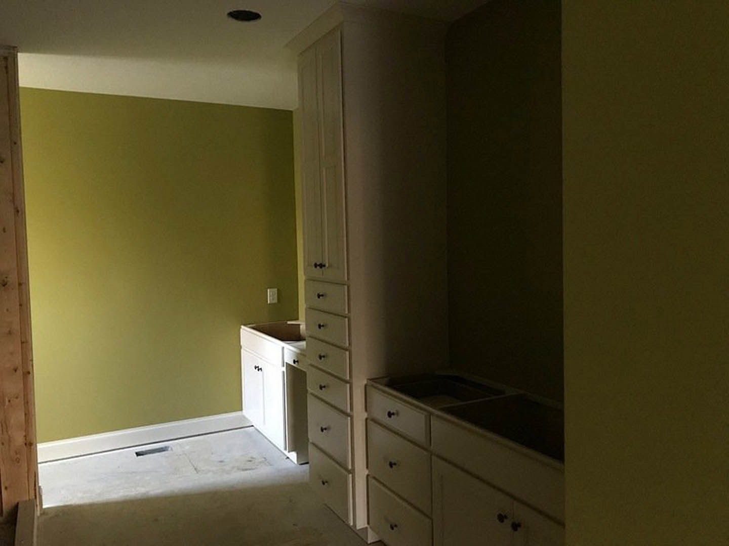 Bathroom with white cabinetry, built-in sink, yellow painted wall, wooden door, and wall-mounted mirror