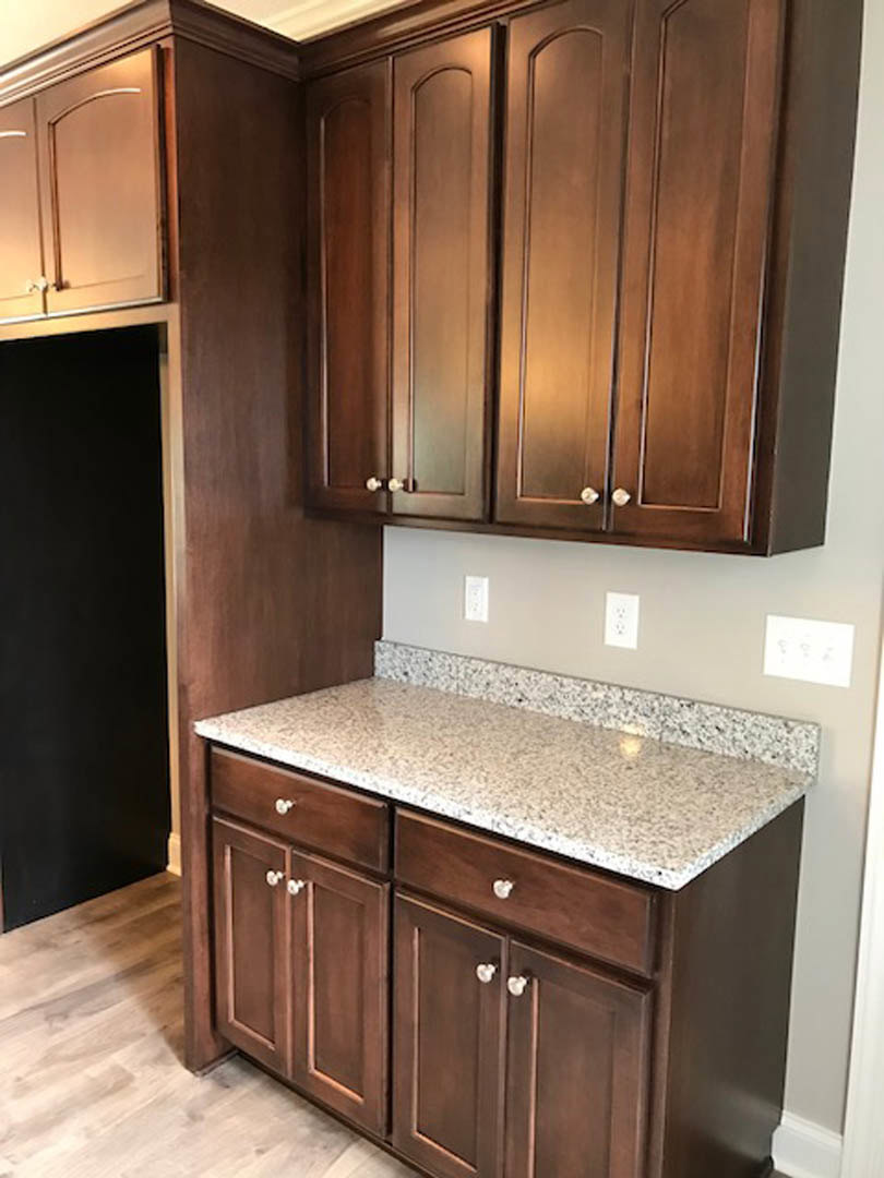 Marble countertop with subtle veining, dark backsplash, wooden lower cabinets, stainless steel appliances, and modern drawer pulls in a contemporary kitchen.