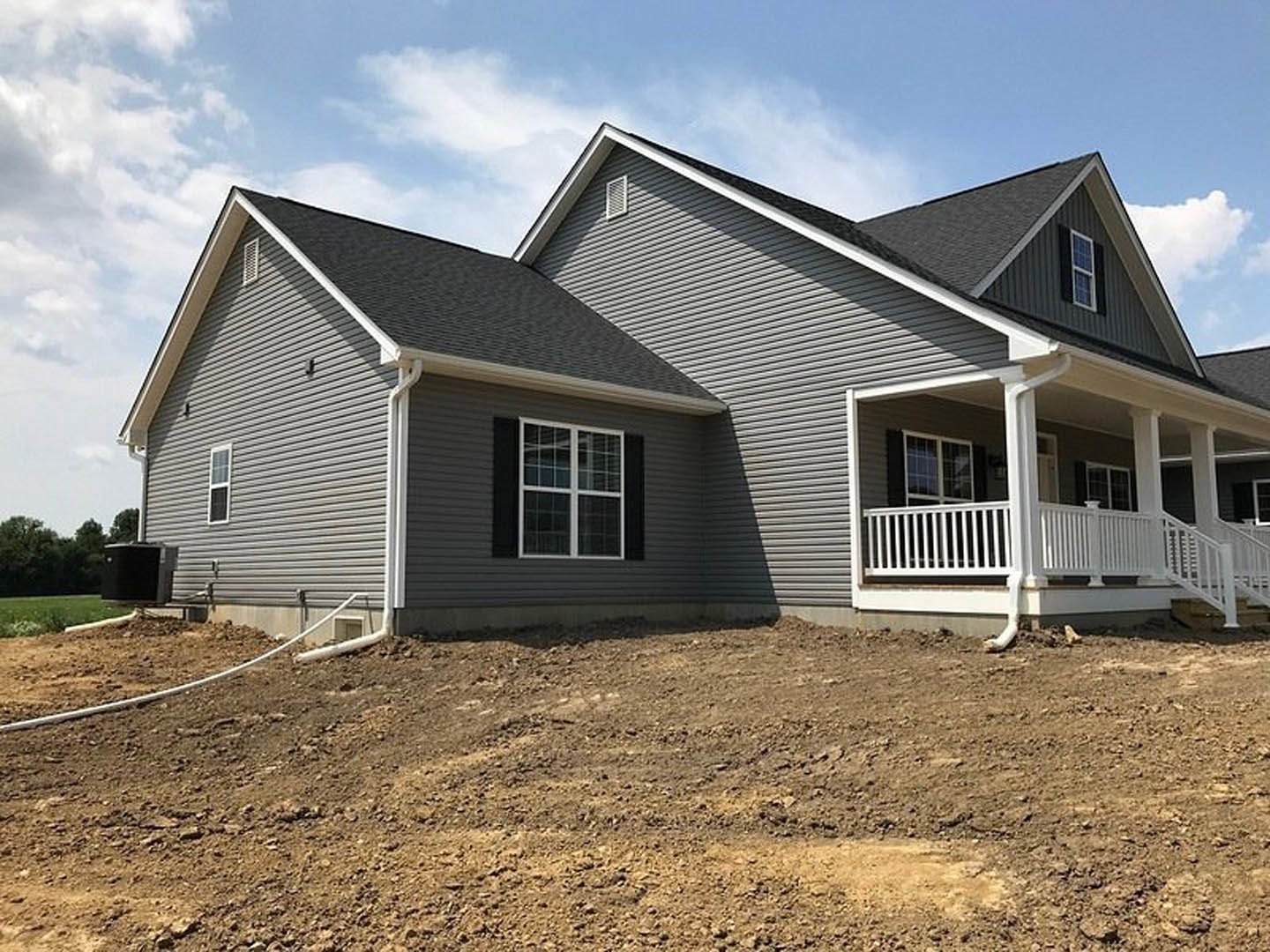 White-framed window and porch with white railing on house exterior, dirt hill in foreground, Robert Frost Farm visible in background, black utility box on grassy field, metal wall