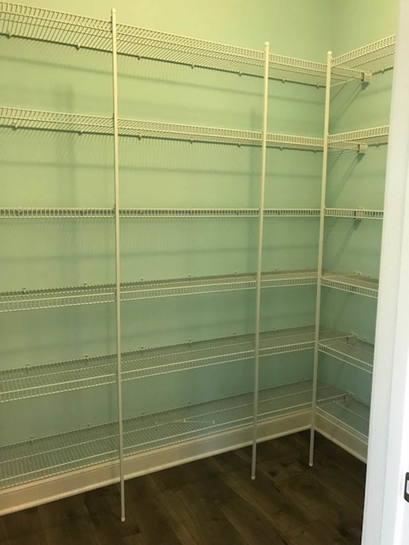 Walk-in closet with white walls, built-in metal shelving, and light wood flooring