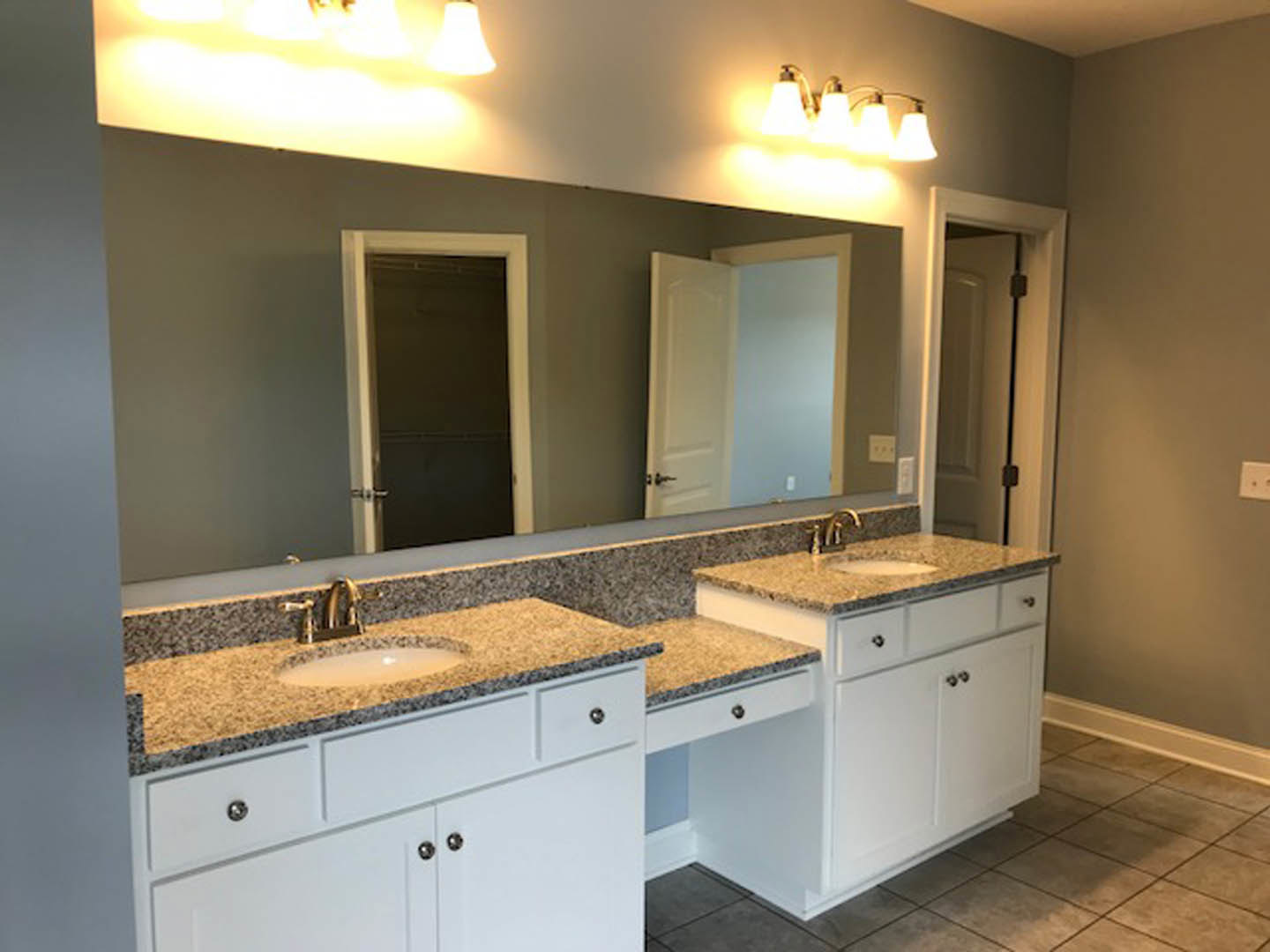 Bathroom featuring marble countertops, expansive wall mirror, white cabinetry, chrome faucet, and tiled flooring