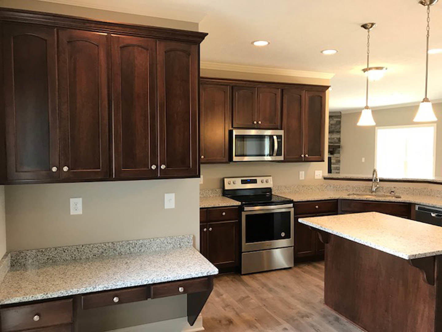 Granite countertops with stainless steel stove, white cabinetry, built-in microwave, and wall outlet in a modern kitchen