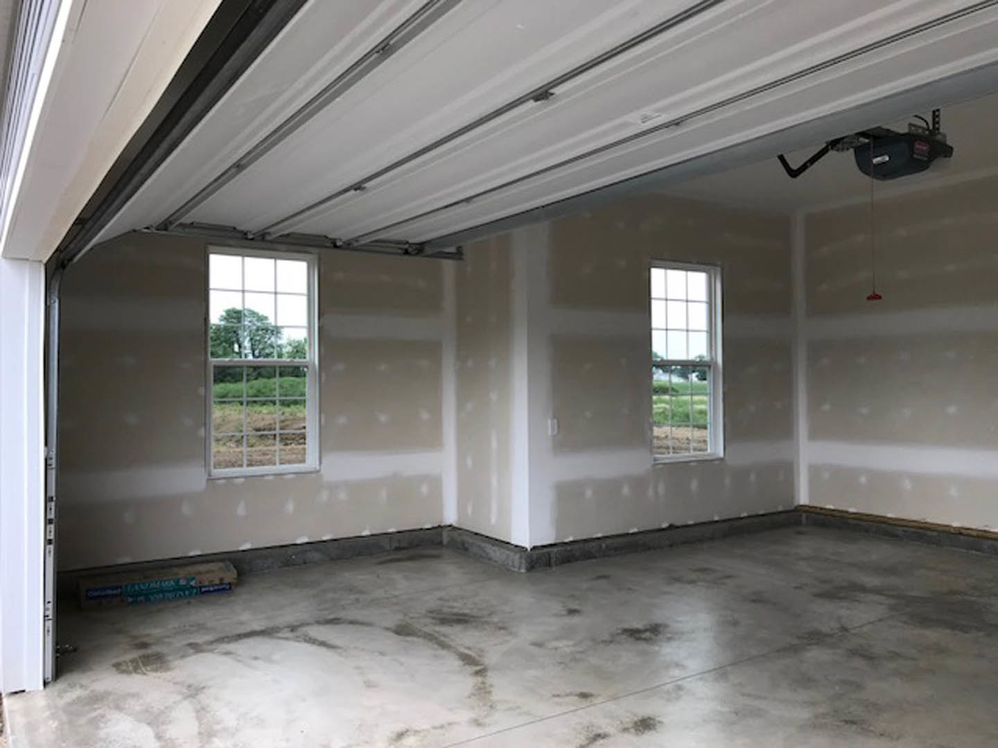 White-walled room with large windows, concrete floor, and views of trees and open field