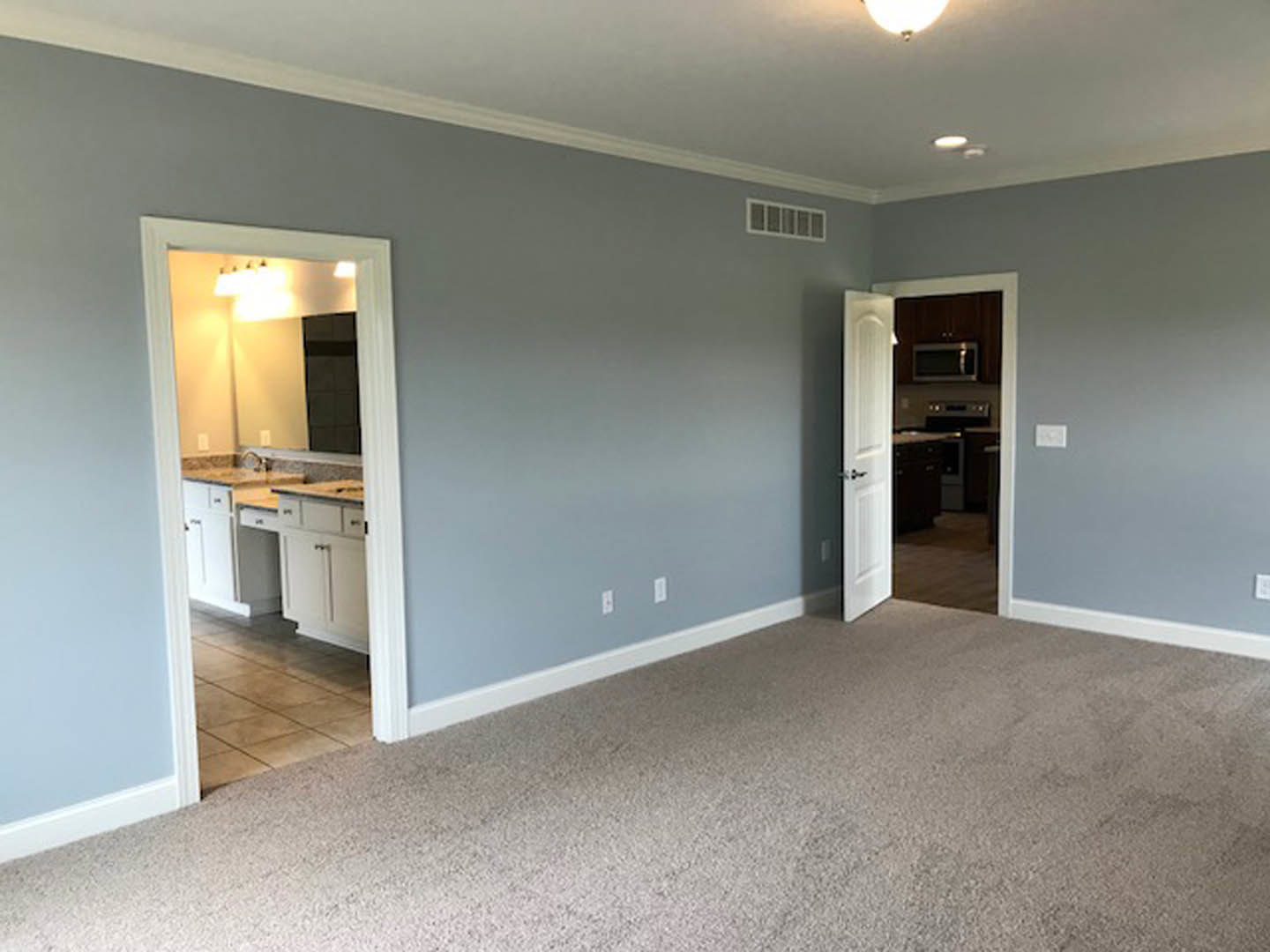 Open-concept kitchen with white cabinetry, two paneled doors, light-colored carpeted floor, plaster walls, and recessed ceiling lighting