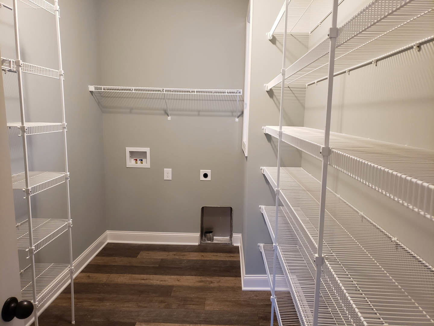 White built-in shelves along a wall in a room with light wood flooring, white ceiling, and a metal handrail near stairs.