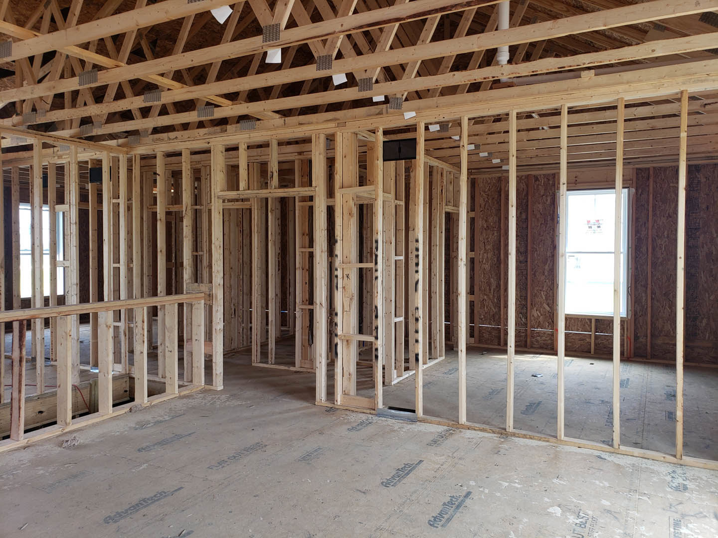 Exposed wood ceiling beams, white-framed window, black cabinet with matching handle, unfinished wooden framing and roof structure, scattered construction papers